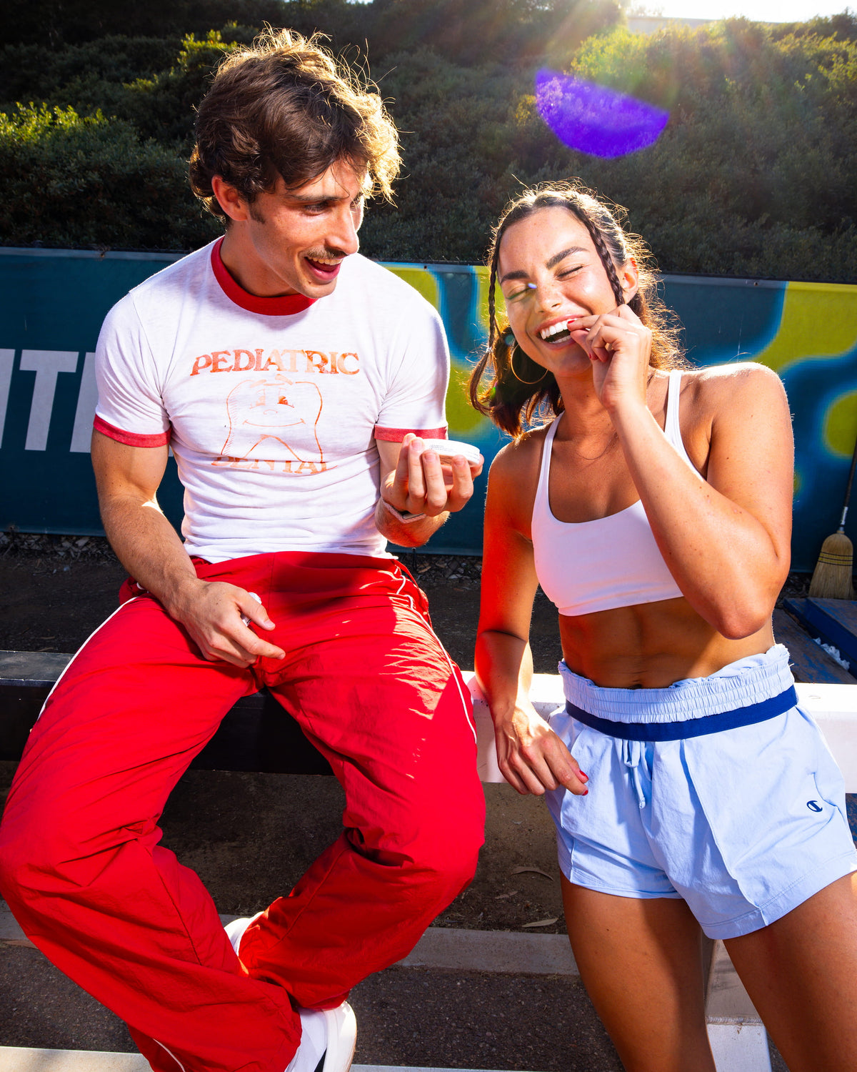 Two people laughing outdoors, one putting in a ZALT electrolyte pouch